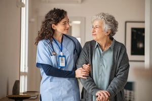 Caregiver assisting senior woman for early mobilisation in ICU