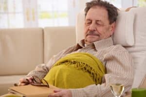 Senior man lying in armchair, fell asleep while reading book.